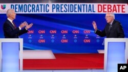 Former Vice President Joe Biden, center, stops to talk with CNN anchor Dana Bash, left, as Sen. Bernie Sanders, I-Vt., right, waves after they participated in a Democratic presidential primary debate at CNN Studios in Washington, Sunday, March 15, 2020.