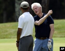 FILE - Then-President Barack Obama, left, talks with former President Bill Clinton, center, as they play golf on the first hole at Farm Neck Golf Club in Oak Bluffs, Mass., on Martha's Vineyard, Aug. 15, 2015.