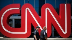 FILE - Security guards walk past the entrance to CNN headquarters in Atlanta.