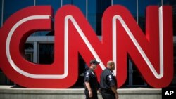 FILE - Security guards walk past the entrance to CNN headquarters in Atlanta. 
