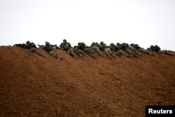 Israeli soldiers are seen next to the border fence on the Israeli side of the border with the northern Gaza Strip, Israel, March 30, 2018.