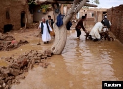 People salvage items from a house destroyed by flood in Enjil district of Herat province, Afghanistan, March 29, 2019.