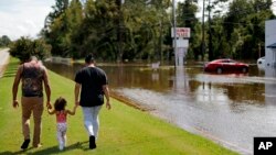 A couple walks with their daughter after checking on their flooded home in the aftermath of Hurricane Florence in Spring Lake, N.C., Monday, Sept. 17, 2018.