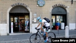 In this image taken on Tuesday, April 14, 2020, Italian professional cyclist Davide Martinelli, rides his bike after collecting medicine at a pharmacy to be delivered to residents in Rovato, near Brescia, Northern Italy. 