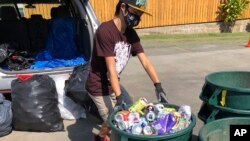 Genshu Price menurunkan kaleng dan botol di pusat daur ulang di Kahaluʻu, Hawaii, Juni 2021. (Maria Price/Bottles4College via AP)
