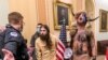 FILE - In this Jan. 6, 2021 file photo, supporters of President Donald Trump, including Jacob Chansley, with fur hat, are confronted by U.S. Capitol Police officers outside the Senate Chamber inside the Capitol in Washington.