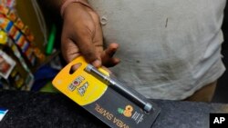 A roadside tobacco shop vendor displays an e-cigarette in New Delhi, India, Sept. 18, 2019.