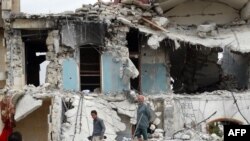 Syrians inspect the damage following a reported US-led coalition air strike against the headquarters of al-Nusra Front, 20 km west of the northern city of Aleppo on Sept. 25, 2014. 
