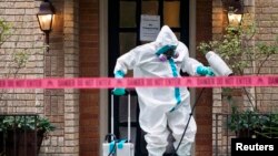 Seorang petugas CG Environmental HazMat mensterilkan pintu masuk ke kediaman seorang anggota tim medis di RS 'Texas Health Presbyterian' yang telah terdampak virus Ebola di Dallas, Texas, 12 Oktober 2014. (Foto: dok).
