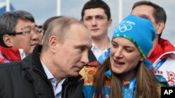 FILE - Russian President Vladimir Putin speaks with Olympic Village Mayor Elena Isinbaeva while visiting the Coastal Cluster Olympic Village ahead of the Sochi 2014 Winter Olympics in Sochi, Russia. 