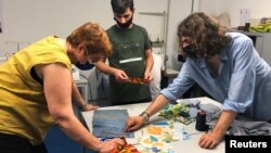 Pencari suaka Afghanistan Haroon Sherzad, mahasiswa desain fashion Hugo Castejon-Blanchard dan relawan komunitas Catherine Chapron di sebuah bengkel kerja di Antony, dekat Paris, Perancis, 11 Juni 2021. (REUTERS/Michaela Cabrera)