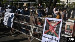 A poster featuring army chief Senior General Min Aung Hlaing is displayed on a barricade as protesters take part in a demonstration against the military coup in front of the Central Bank of Myanmar in Yangon, Feb. 11, 2021.