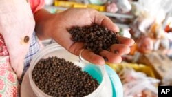 A vendor holds a handful of Kampot pepper before selling at a market in Phnom Penh, Cambodia, Tuesday, March 1, 2016.
