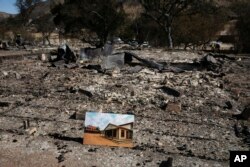 A photo of what the area looked like before is placed on the remains of a building leveled in the Woolsey Fire at decimated Paramount Ranch, during U.S. Interior Secretary Ryan Zinke's visit to the ranch, Nov. 15, 2018, in Agoura Hills, Calif.