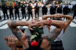 Protesters kneel in front of New York City Police Department officers before being arrested for violating curfew beside the iconic Plaza Hotel on 59th Street, June 3, 2020, in New York.