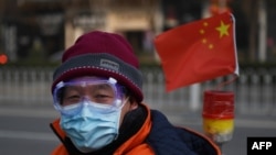 一名戴着口罩和眼罩的男子行走在北京街头。（2020年2月12日）