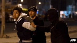 FILE - Tunisian security forces detain a protester on the outskirts of Tunis, Jan. 10, 2018.