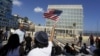 FILE - A woman waves a U.S flag in front of the U.S. Interests Section, in Havana, July 20, 2015.
