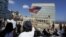 FILE - A woman waves a U.S flag in front of the U.S. Interests Section, in Havana, July 20, 2015.