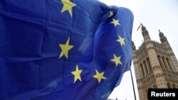 Seorang pengunjuk rasa anti-Brexit mengibarkan bendera Uni Eropa di seberang Gedung Parlemen di London, Inggris, 10 Desember 2018. (Photo: REUTERS/Toby Melville)
