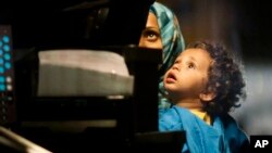 A woman and child look at a police officer as they board a bus, after they and other refugees were made to unboard a train by German border police officers, at the train station of the southern German border town of Passau, Germany, Monday, Sept. 14, 2015. (AP Photo/Markus Schreiber)