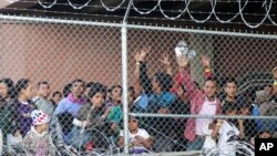 FILE - Central American migrants wait for food in El Paso, Texas, March 27, 2019, in a pen erected by U.S. Customs and Border Protection to process a surge of migrant families and unaccompanied minors. 