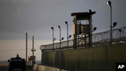 Seorang tentara AS berdiri di atap kendaraannya dengan membawa dengan senapan mesin (kiri), sementara seorang penjaga mengamati sekitarnya dari sebuah menara di penjara Teluk Guantanamo, Kuba (Foto: dok).