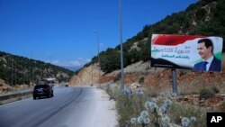 In this Friday, July 20, 2018, photo, a poster of President Bashar Assad with Arabic that reads "Welcome in victorious Syria." is seen on the border between Lebanon and Syria. 