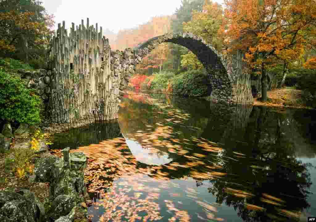 Fog hangs over trees in autumnal colors and the so-called Rakotzbruecke bridge of the Rhododendronpark Kromlau landscaped park in Kromlau, eastern Germany, Oct. 27, 2015.