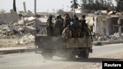 Des rebelles passent devant des bâtiments en ruine à al-Rai town, au nord d'Alep, Syrie, le 2 octobre 2016. 