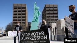 FILE - Opposing groups of demonstrators attend a gathering outside the Georgia State Capitol to protest HB 531, which would place tougher restrictions on voting in Georgia, in Atlanta, Georgia, March 8, 2021. 