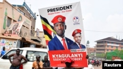 A supporter of Ugandan opposition Presidential candidate Robert Kyagulanyi also known as Bobi Wine, carry his electoral campaign poster ahead of the presidential and parliamentary elections, in Kampala, Uganda, Jan. 12, 2021.