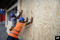 A worker nails a board to a storefront window as protection against Hurricane Matthew in Kingston, Jamaica, Oct. 1, 2016.