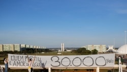 Artists hold a banner reading "Who's gone is someone's love, 30,000 dead" amid the coronavirus disease (COVID-19) outbreak in Brasilia
