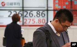 People stand by an electronic stock board of a securities firm in Tokyo, Monday, Dec. 3, 2018. Shares are advancing in Asia following the meeting between Presidents Donald Trump and Xi Jinping.