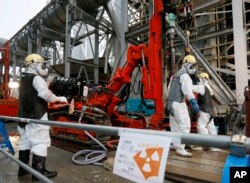 FILE - Workers drill pipes into the ground to be used to create a frozen underground wall to surround the crippled reactor buildings, Fukushima, Japan.