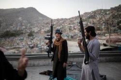 Pejuang Taliban memegang senjata mereka saat mereka berdiri di atas sebuah bangunan di kuil Kart-e-Sakhi di Kabul, Afghanistan, Selasa, 19 Oktober 2021. (AP Photo/Ahmad Halabisaz)