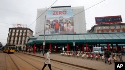 A man walks under a poster advertising the TV Series ‘Zero’, at Cadorna square in Milan, Italy, April 27, 2021. 