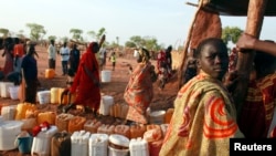 A refugee waits to collect water from a well.