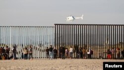 Migran, bagian dari ribuan kafilah yang berusaha mencapai AS, melihat melalui pagar perbatasan antara Meksiko dan Amerika Serikat setibanya di Tijuana, Meksiko, 13 November 2018.