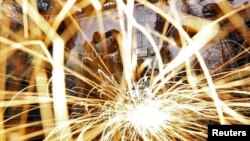 FILE - A worker grinds an iron window frame used in a dairy machine at a manufacturing unit in the western Indian city of Ahmedabad, India.