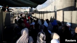 Israeli border police officers (L) stand guard as Palestinians wait to cross through the Qalandia checkpoint as they make their way to attend the first Friday prayer of the holy fasting month of Ramadan in Jerusalem's al-Aqsa mosque, near the West Bank city of Ramallah June 10, 2016. 