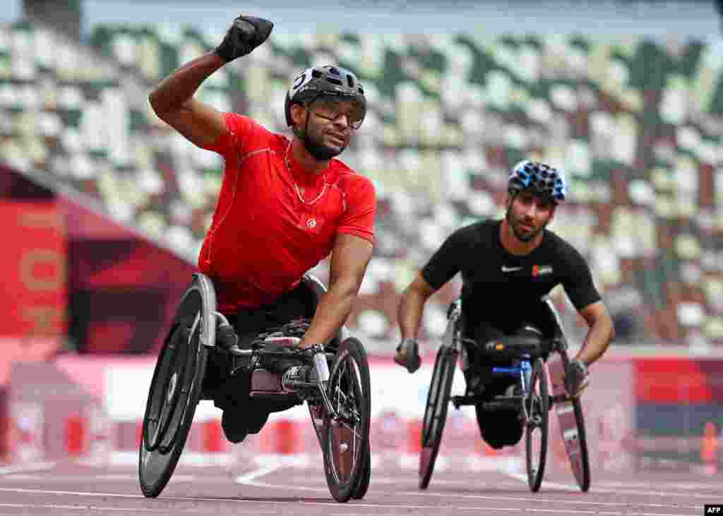 Tunisia&#39;s Walid Ktila (L) reacts following his winning race in the men&#39;s 100m (T34) final during the Tokyo 2020 Paralympic Games at the National Stadium in Tokyo on August 30, 2021. (Photo by Kazuhiro NOGI / AFP)
