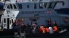 Pejabat Pasukan Perbatasan Inggris memindahkan migran yang dicegat saat bepergian dengan RIB dari Perancis ke Dover, Inggris tenggara pada 13 Agustus 2021. (Foto: AFP)