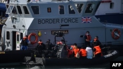 Pasukan Perbatasan Inggris memindahkan migran yang dicegat saat bepergian dengan RIB dari Prancis ke Dover dari Kapal Patroli ke Pasukan Perbatasan HMC Speedwell di Dover, Inggris tenggara pada 13 Agustus 2021. (Foto: AFP)