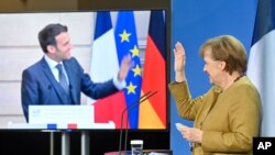 German Chancellor Angela Merkel waves to French President Emmanuel Macron at the end of a press conference following German-French Security Council video talks in Berlin, Germany, Feb. 5, 2021.