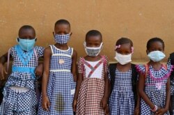 FILE - Children wearing face masks gather outside their classroom at a school in Attecoube, popular district of Abidjan, Ivory Coast, May 25, 2020.