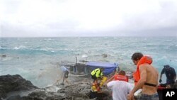 Petugas pertolongan berusaha menyelamatkan penumpang kapal pencari suaka yang pecah menabrak tebing karang di pulau Christmas (foto: Desember 2010). 