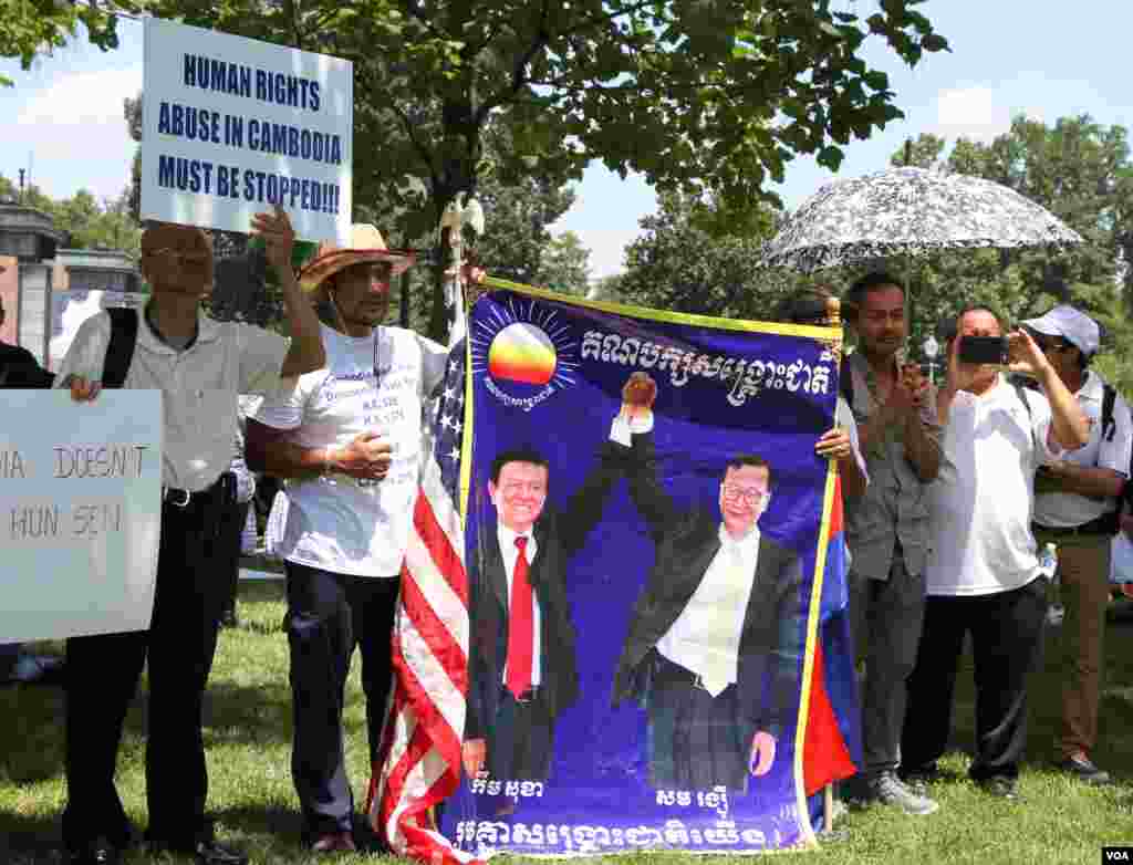 អ្នកចូលរួម​កាន់​បដា​រូប​លោក កឹម សុខា និងលោក សម រង្ស៊ី មេដឹកនាំ​គណបក្ស​ប្រឆាំង នៅក្នុង​ការ​ប្រមូល​ផ្តុំ​គ្នា​មួយ នៅ​ក្បែរ​រដ្ឋ​សភា​អាមេរិក រដ្ឋធានី​វ៉ាស៊ីនតោន ថ្ងៃទី១៧ ខែកក្កដា ឆ្នាំ២០១៩។ លោក កឹម សុខា កំពុង​ត្រូវបាន​រដ្ឋាភិបាល​កម្ពុជា​ឃុំ​ខ្លួន​នៅក្នុង​គេហដ្ឋាន​របស់​លោក​នៅ​រាជធានី​ភ្នំពេញ រីឯ​លោក​ សម រង្ស៊ី កំពុង​និរទេសខ្លួន​រស់នៅ​ប្រទេស​បារាំង។ (ទែន សុខស្រីនិត/VOA)