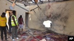 Warga memeriksa sebuah masjid yang rusak akibat ledakan di Maiduguri, Nigeria, 23 Oktober 2015. Boko Haram dicurigai berada di balik pengeboman tersebut. (AP Photo/Jossy Ola)